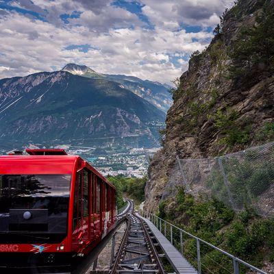 Red Swiss funicular from Sierre to Crans Montana, Valais Canton, Switzerland. Public transport cable car with scenic view over the city and mountain.