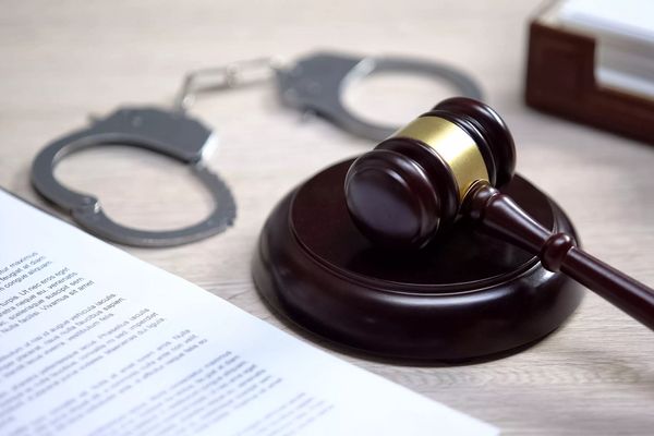 Handcuffs on table, gavel lying on sound block, crime punishment, law order