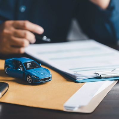 Businesswoman signing car insurance document or lease paper. Writing signature on contract or agreement. Buying or selling new or used vehicle. Car keys on table. Warranty or guarantee.