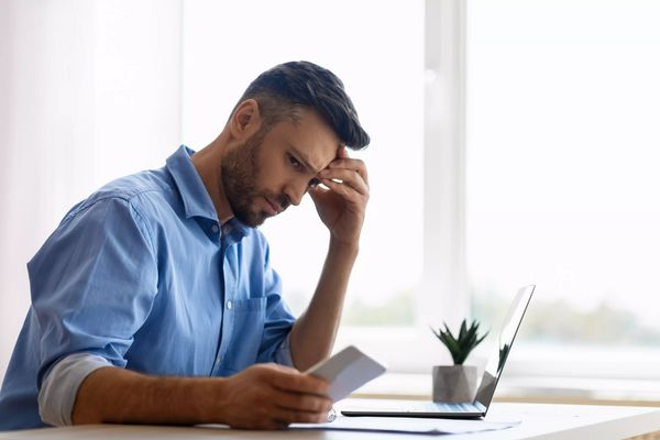 Concerned young businessman looking at smartphone while working in office, waiting message
