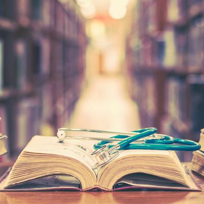 Old book in library with stethoscope on open textbook, stack pil